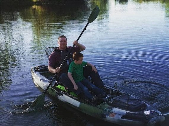 A father and son share time in the kayak (near the shore).