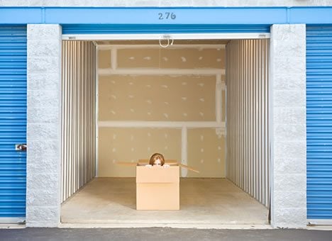 Girl inside cardboard box, large showing storage unit with blue doors