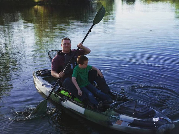 A father and son share time in the kayak (near the shore).