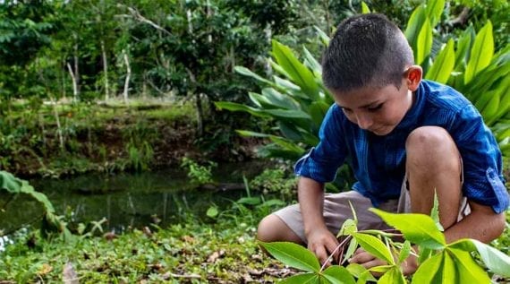 Photo of a young boy by a river in, presumably, Costa Rica