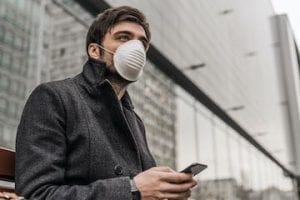 Man wearing a mask holding a smartphone