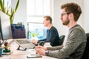 Image of two male digital workers in front of computer screens