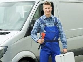 Photo of a plumber in front a van holding a pipe wrench