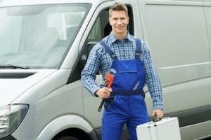 Photo of a plumber in front a van holding a pipe wrench