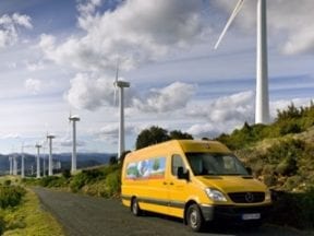 Image of a DHL delivery truck driving beneath windmills on a road