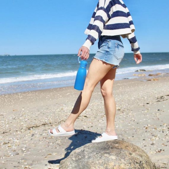 Girl standing on a rock holding a bottle of water.  Source: TakeyaUSA.com.
