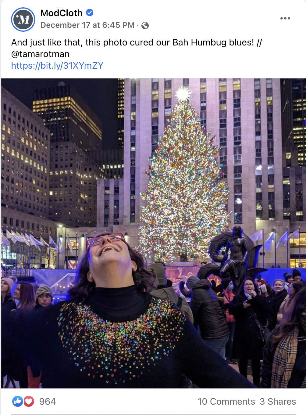 Image from Facebook of a photo from ModCloth's page showing a female outdoors in a city in front of a Christmas tree