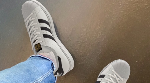 Screenshot on phone of two male feet wearing Adidas sneakers