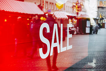 Image of a retail window with a prominent red "sale" sign.