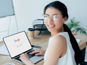 Woman smiling while using laptop with Google website on screen
