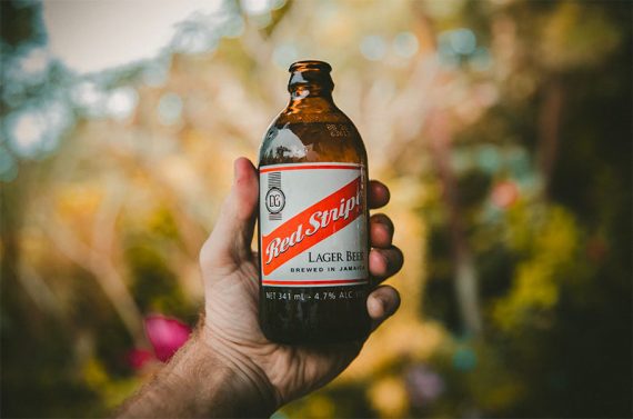 Image of a hand holding a Red Stripe lager beer. 