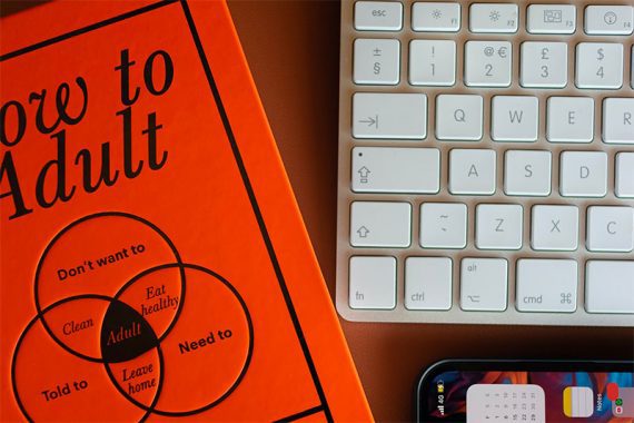 Photo d'une couverture de livre, d'un clavier et d'un smartphone sur un bureau.