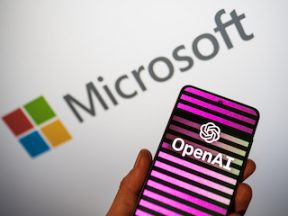 OpenAI logo on phone in a hand and blurred Microsoft