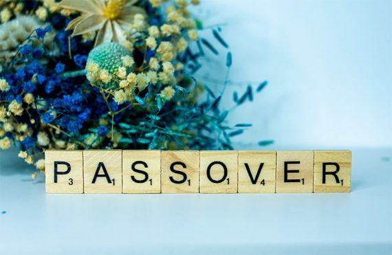 Photo of flowers with Scrabble letters in front reading" Passover."