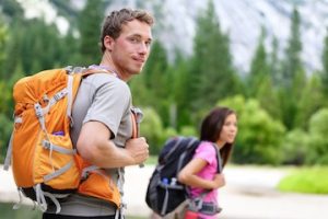 A 20s male and female hiking outdoors wearing backpacks