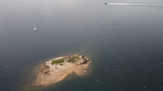 Aerial photo of an island with two boats in the water nearby.