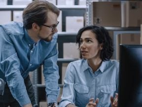 Photo of a male and female in a warehouse looking at a computer