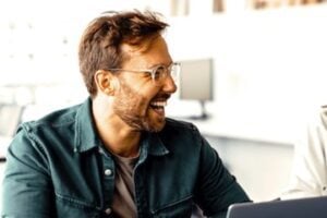 Male laughing in front of a laptop