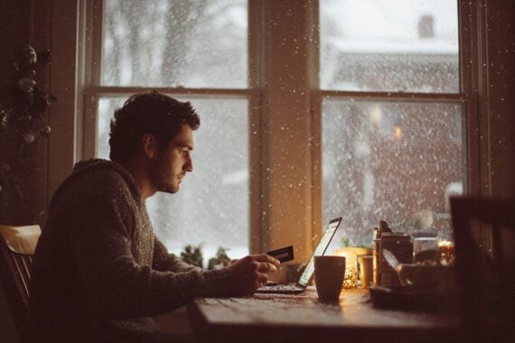 Photo of a male looking at a laptop with snow in the background Photo of a male looking at a laptop with snow in the background