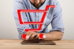 Image of male looking at a tablet computer with a shopping cart icon on top