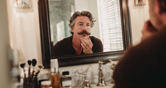 Homem com um bigode olhando em um espelho Homem com um bigode olhando em um espelho