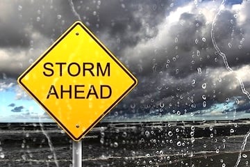 Road sign reading "Storm Ahead" amid a rain storm