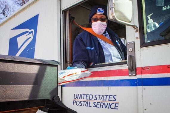 Photo of a U.S. Postal Service driver putting items in a mailbox Photo of a U.S. Postal Service driver putting items in a mailbox