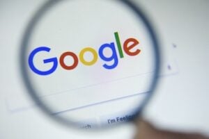 Google logo and search page behind a magnifying glass
