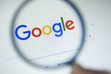 Google logo and search page behind a magnifying glass
