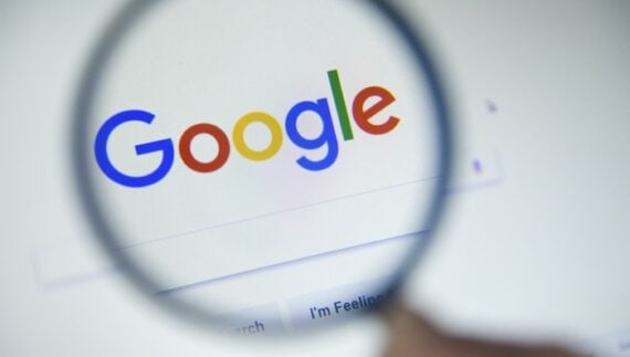 Google logo and search page behind a magnifying glass