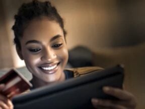 Image from Firmly of a female holding a credit card while looking at a laptop