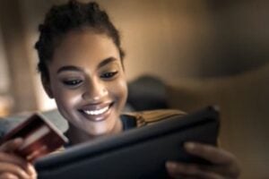 Image from Firmly of a female holding a credit card while looking at a laptop