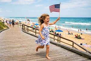 Pre-school aged girl waving a flag by an ocean beach