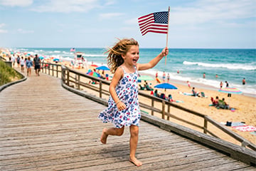 Pre-school aged girl waving a flag by an ocean beach