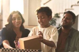 Image from Veho of a mom, dad, and preschool child opening a box