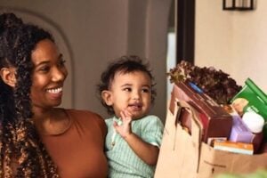 Instacart image of a mom and baby receivng a sack of groceries