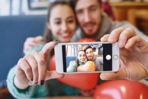 Male and female influencers behind a smartphone camera