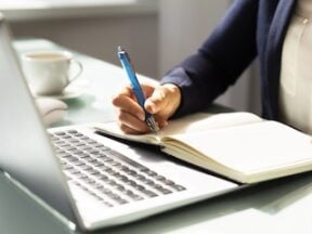Image of a writer holding a pen next to a keyboard