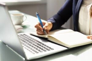 Image of a writer holding a pen next to a keyboard