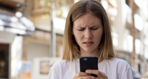Female holding a phone with a frustrated look on her face Female holding a phone with a frustrated look on her face